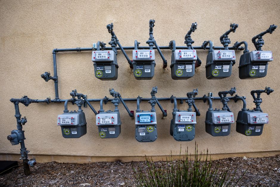 Multiple gas meters mounted on a stucco exterior wall, representing commercial plumbing utility infrastructure in Fresno, CA.