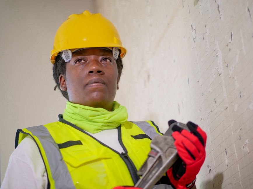 Female plumber in safety gear holding a wrench, ready to provide residential plumbing services in Livingston, CA