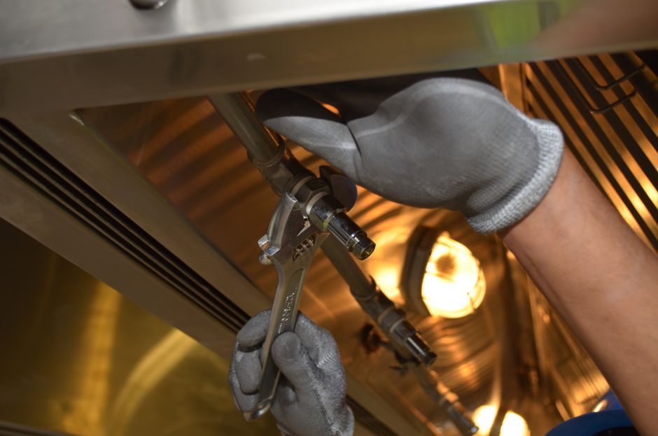 Plumber repairing pipes with wrench and gloves — professional plumbing service in Madera, CA
